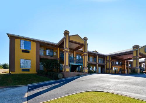 a large yellow building with a large driveway at Peach State Inn & Suites in Hawkinsville