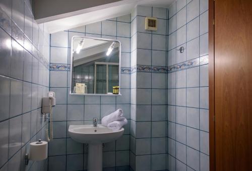 a blue tiled bathroom with a sink and a mirror at Hotel Kastoria in Kastoria City in Kastoria