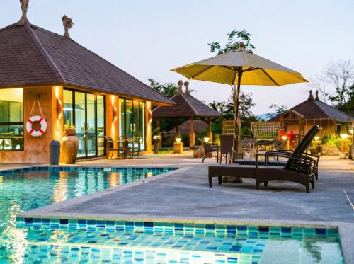 a pool with chairs and an umbrella next to a house at Katiliya Park Villa in Mae Chan