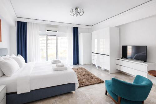 a white bedroom with a large bed and a blue chair at White Tower Mamaia Beach 505 in Mamaia