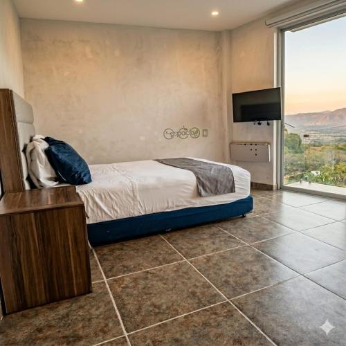 a bedroom with a bed and a flat screen tv at Amanecer Ixtapan de la Sal in Ixtapan de la Sal