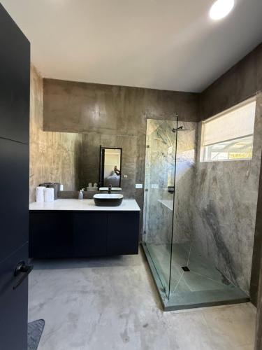 a bathroom with a glass shower and a sink at Casa Frank - Sophiassuites506 in Brasilito