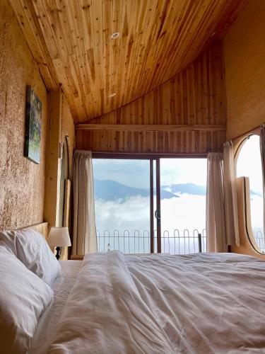a bedroom with a large bed with a large window at Phỏng Lài Mountain Homestay - Ta Xua Peak View in Bắc Yên