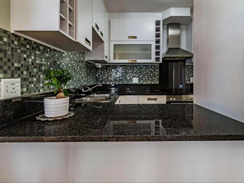 a kitchen with black counter tops and white cabinets at 75 Cap D'Azur in Strand