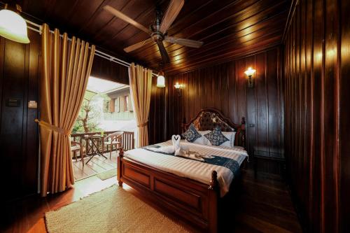 a bedroom with a bed with a ceiling fan at Bualuang Hotel in Luang Prabang