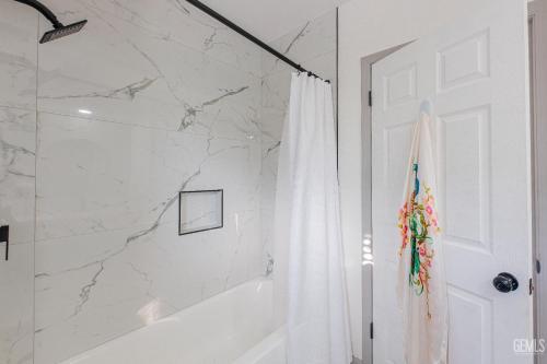 a white bathroom with a shower and a shower curtain at Luxury Stay Near Downtown Bakersfield in Bakersfield