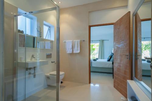 a bathroom with a toilet and a glass shower at Greenways Drive Apartment in Kommetjie