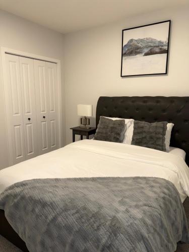 a bedroom with a large bed with a black headboard at Modern Comfort in Calgary