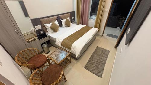 a bedroom with a bed and chairs and a balcony at Hotel Kedarkhand in Sonprayag
