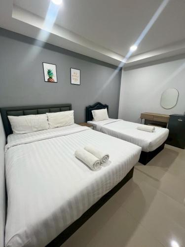 two beds in a room with white sheets at อยู่สบายเพลส in Chonnabot