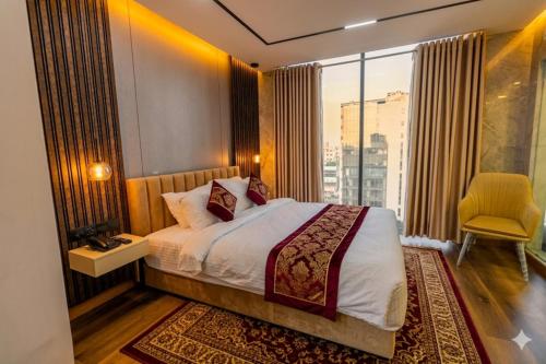 a bedroom with a bed and a window with a yellow chair at Monsoon Courtyard Luxury Hotel in Dhaka