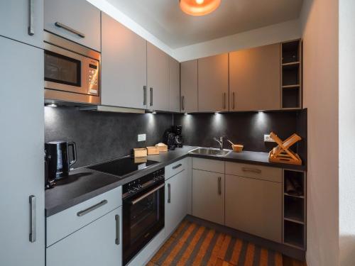 a kitchen with white cabinets and black counter tops at Kitzbühel alpine lodge with sauna in Mittersill