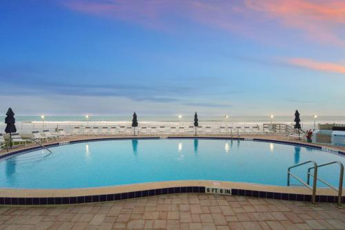 a large swimming pool with a beach in the background at Paradise Beach Club - Oceanfront and Penthouse in Satellite Beach