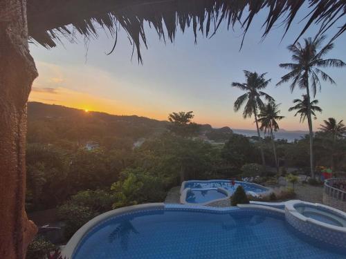 a resort pool with a view of the sunset at May Three Farm in Puerto Galera