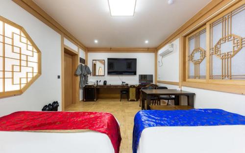 a room with two beds and a table and a desk at Manwol Hotel Yuseong in Daejeon