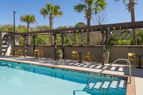 a swimming pool with chairs and tables and palm trees at Home2 Suites By Hilton Jacksonville Airport in Jacksonville