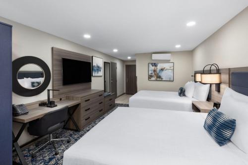 a hotel room with two beds and a desk at Wyndham DFW Airport in Irving