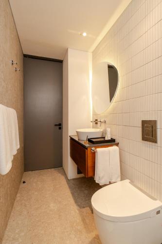 a bathroom with a white toilet and a sink at Ecoverse Resort & Residence by OXO - Nyanyi Beach, Bali in Cemagi