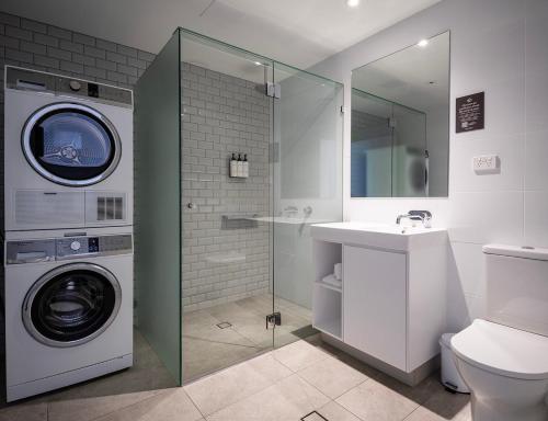 a bathroom with a washing machine and a sink at Quest Robina in Gold Coast