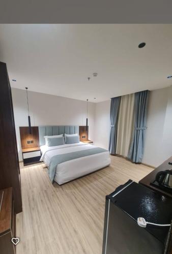 a bedroom with a large white bed and a television at Makarim Al Nakheel serviced apartments in Rabigh