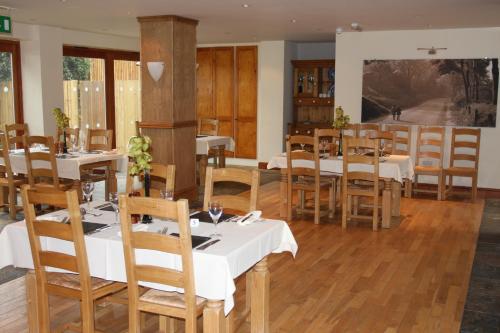ピカリングにあるCottage Lea's Country Hotel & Restaurantの白いテーブルと木製の椅子が備わるレストラン