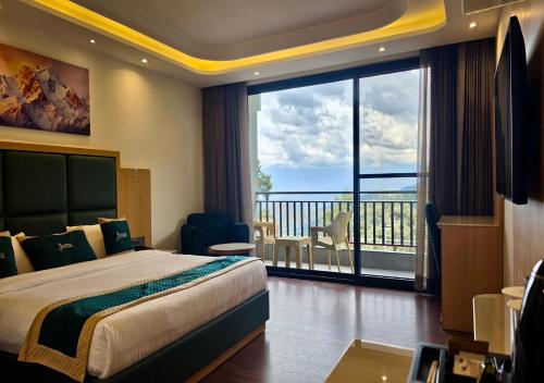 a hotel room with a bed and a large window at Jeeva Premium Rooms in Dalhousie