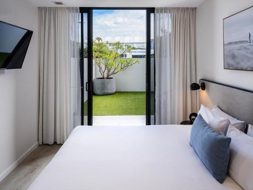 a bedroom with a large white bed and a window at Quest Robina in Gold Coast