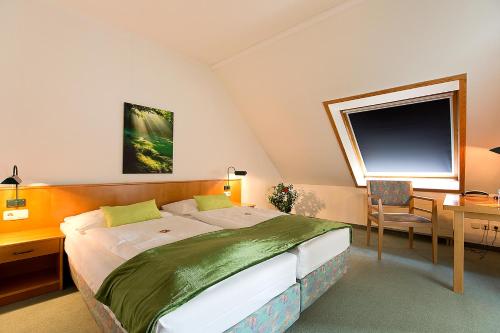 Schlafzimmer mit einem großen Bett, einem Schreibtisch und einem Fenster in der Unterkunft Apart Hotel Gera in Gera