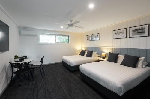 a hotel room with two beds and a table at Settlers Inn in Port Macquarie