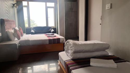 a hotel room with two beds and a chair at Zemu Gangtok in Gangtok