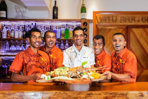 a group of men standing behind a table with a plate of food at Maui Palms in Korolevu