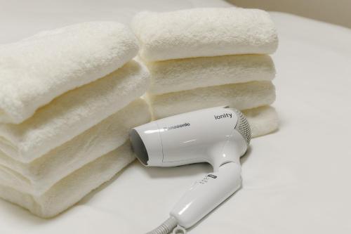 a hair dryer sitting next to a pile of towels at 'Yoyogi House' 10min Walk Shinjuku&Shibuya in Tokyo