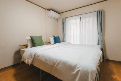 a large white bed in a room with a window at 'Yoyogi House' 10min Walk Shinjuku&Shibuya in Tokyo