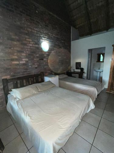 two beds in a room with a brick wall at Lapa Lê Lê Lodge in Ellisras