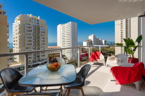 a balcony with a table and chairs and a view of the city at McRamé Design Apt Sea View, Beachfront, Swimming Pool, 2BDR, 2BAR, 6 pax, Praia da Rocha in Portimão