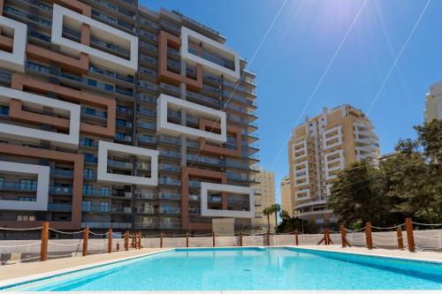 a swimming pool in front of a tall building at McRamé Design Apt Sea View, Beachfront, Swimming Pool, 2BDR, 2BAR, 6 pax, Praia da Rocha in Portimão