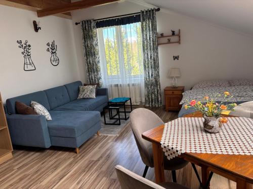a living room with a blue couch and a table at Pod akacjami in Baligród