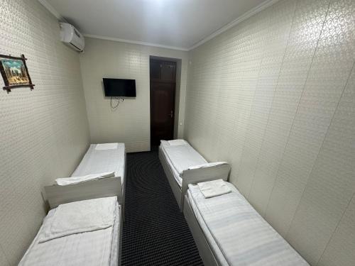 a hospital room with three beds and a tv at Bilol Guest House in Samarkand