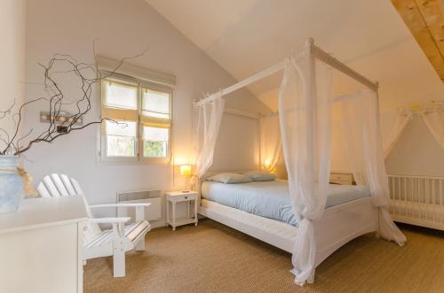 a bedroom with a canopy bed and a chair at L'olifred in Mathaux