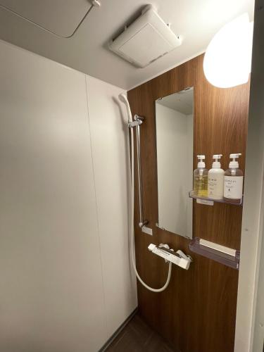 a bathroom with a shower and a mirror at Guest House Kura in Suzaka
