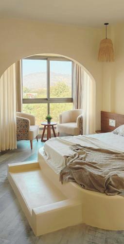a bedroom with a large bed and a large window at Zumi Stays in Udaipur