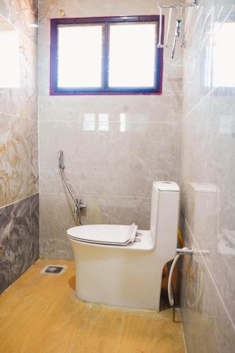 a bathroom with a toilet with a window in it at Sumiwhitehouse in Vallam