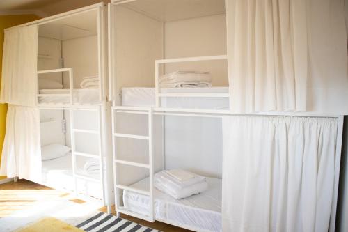 a room with white bunk beds with white curtains at Bombarda 51 - Inn & Hostel in Vila Praia de Âncora