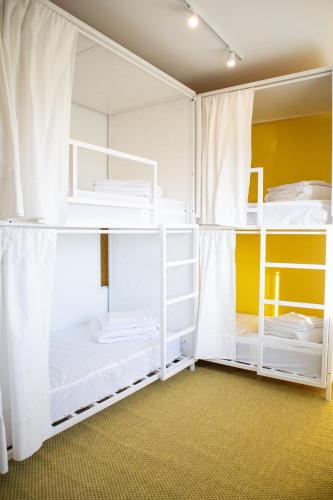two white bunk beds in a room with yellow walls at Bombarda 51 - Inn & Hostel in Vila Praia de Âncora