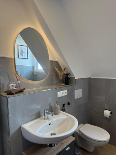 a bathroom with a sink and a toilet and a mirror at Ferienwohnung Eifelhirsch in Ettringen