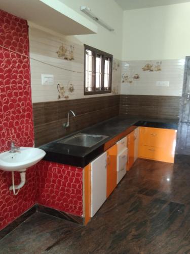 a kitchen with a sink and a red wall at Peter's villa in Kuttālam