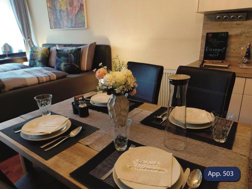 a living room with a table with plates and flowers at Fewo Eisvogelnest in Sankt Englmar