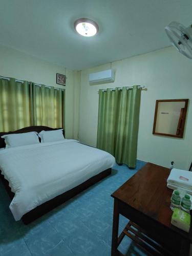 a bedroom with a large bed and a table with a table at Khopchai Guesthouse in Ban Houayxay