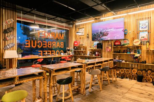 a restaurant with wooden tables and chairs and a large screen at Jeju EQ Stay Hotel in Jeju