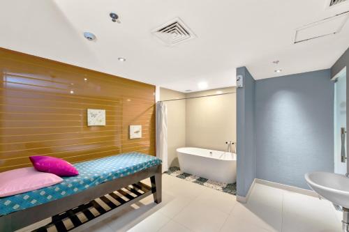 a bathroom with a bench and a tub and a sink at Hotel Ciputra Cibubur managed by Swiss-Belhotel International in Cibubur